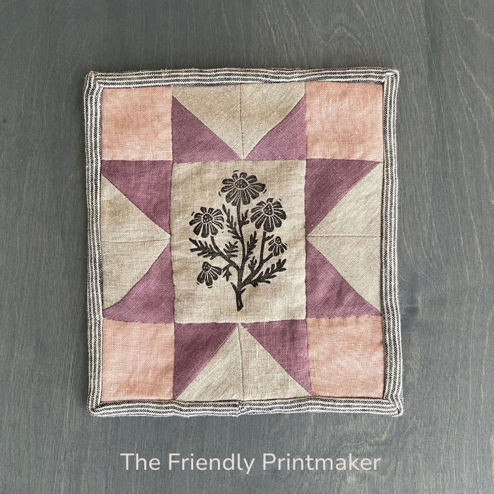 small linen quilt made with a large center rectangle featuring a chamomile block-printed wildflower patch.